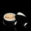 A black jar with a gold lid on a black background.